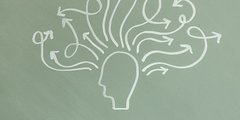 Liitutaululle piirretty pään siluetti. Päästä lähtee useita kiemuraisia nuolia.