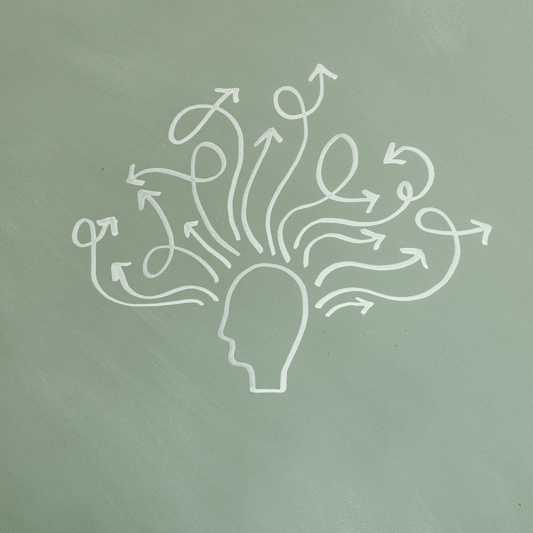 Liitutaululle piirretty pään siluetti. Päästä lähtee useita kiemuraisia nuolia.